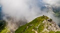 Young woman summerÃÂ hiker with backpack resting on hill onÃÂ steep slopes, panoramic peaks andÃÂ mountains withÃÂ cloudy fog valleys Royalty Free Stock Photo